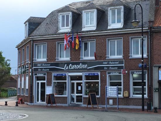 un edificio en una calle con banderas delante en La Caroline en Corbie