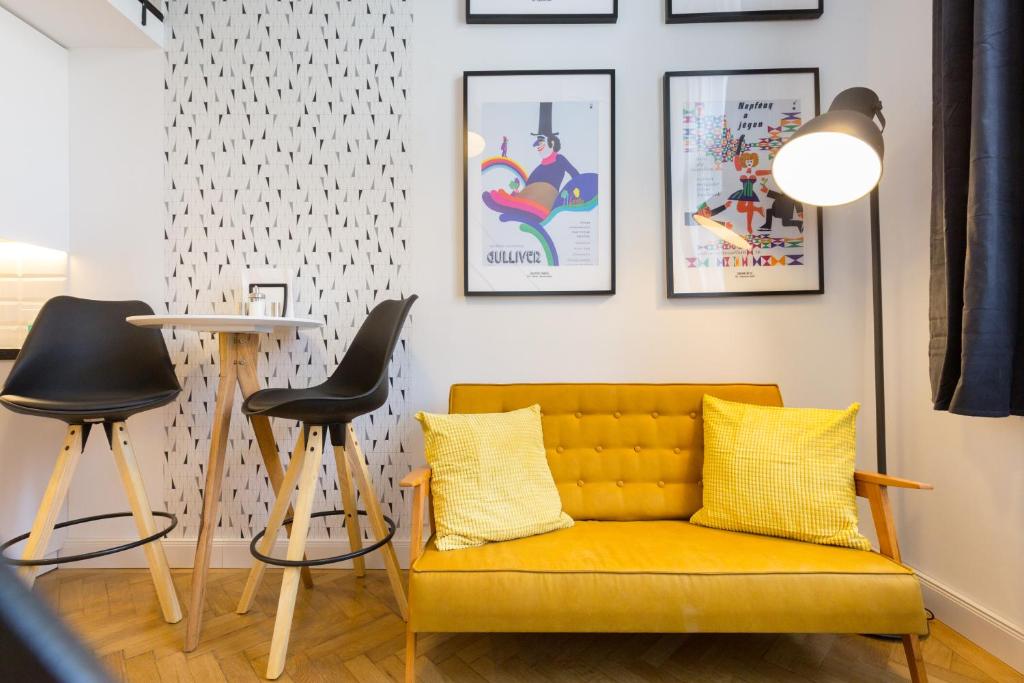 ein Wohnzimmer mit einem gelben Sofa und 2 Hockern in der Unterkunft Leah Studios in Budapest