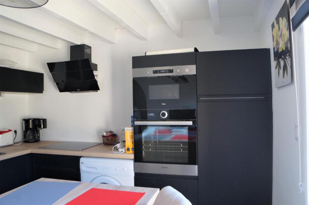 a kitchen with a black refrigerator and an oven at Maisonnette 4 pers- Piscine commune - Plage à 500 m- AESA in Guidel-Plage