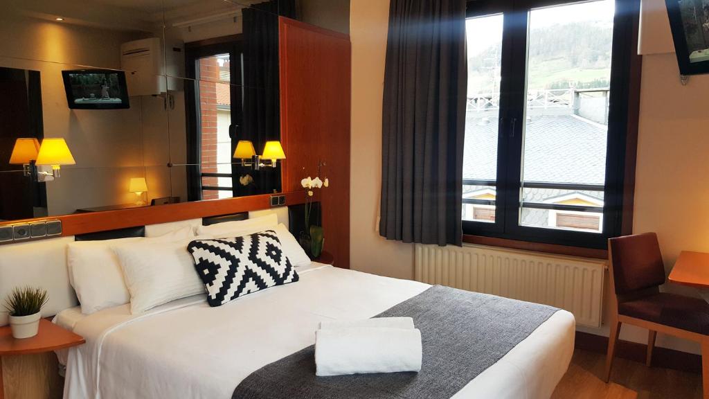 una camera d'albergo con un letto bianco e una finestra di Hotel Oria a Tolosa