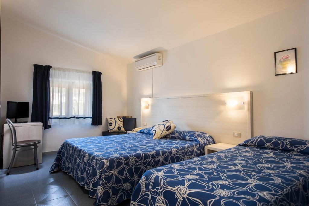 a hotel room with two beds and a window at Hotel La Playa in Cala Gonone