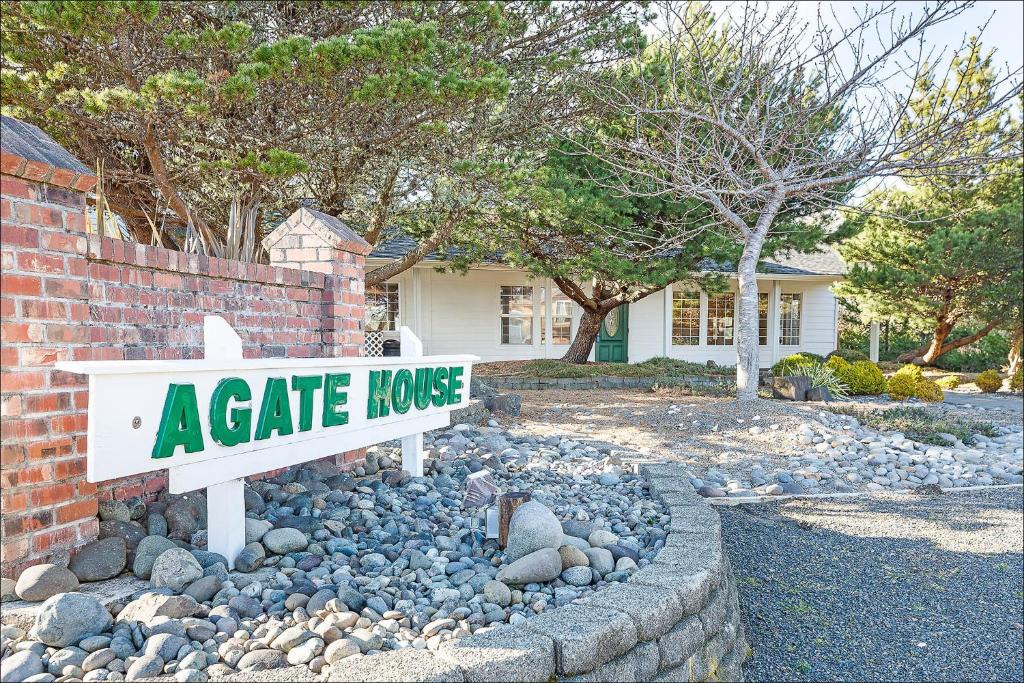 a gate house sign in a bed of rocks in front of a house at Agate House - Ocean Shores in Ocean Shores