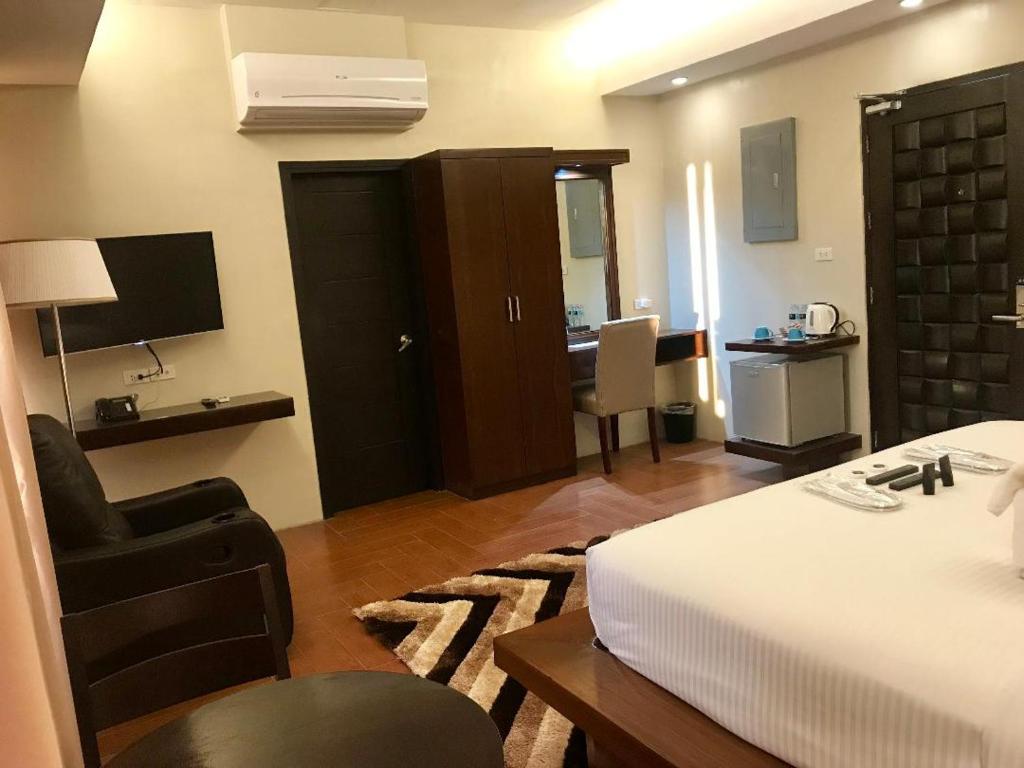 1 dormitorio con cama, silla y escritorio en Treasure Island Hotel With Mini Water Adventure, en Masbate