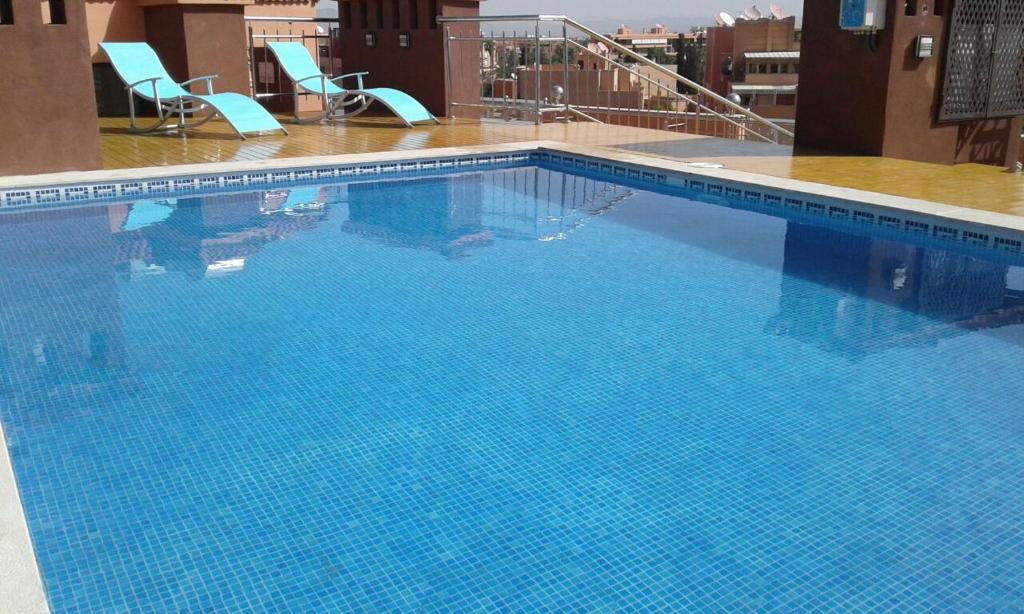 a large blue swimming pool with two chairs on a building at Palm Menara Hotel Marrakech in Marrakech