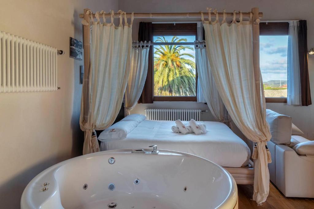 ein Bad mit einer Badewanne, einem Bett und einem Fenster in der Unterkunft Somo Garden Villas in Somo