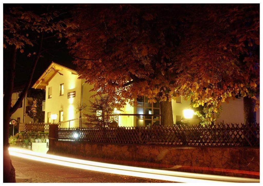a building with a fence in front of it at night at Gästehaus Hubertus Bad Aibling in Bad Aibling
