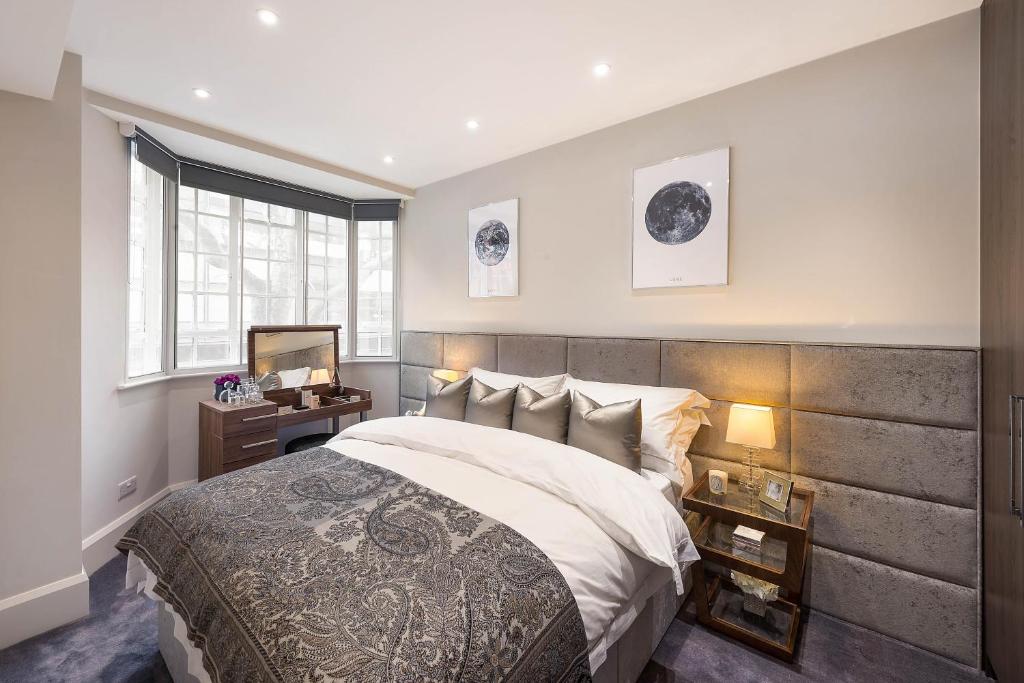ein Schlafzimmer mit einem großen Bett und einem Spiegel in der Unterkunft Beautiful Chelsea Apartment in Fashion District in London
