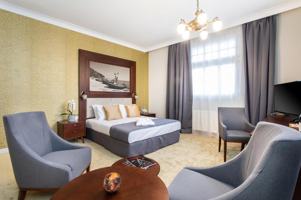 Jakubowy Hotel في غدينيا: غرفة فندقية بسرير وطاولة وكراسي