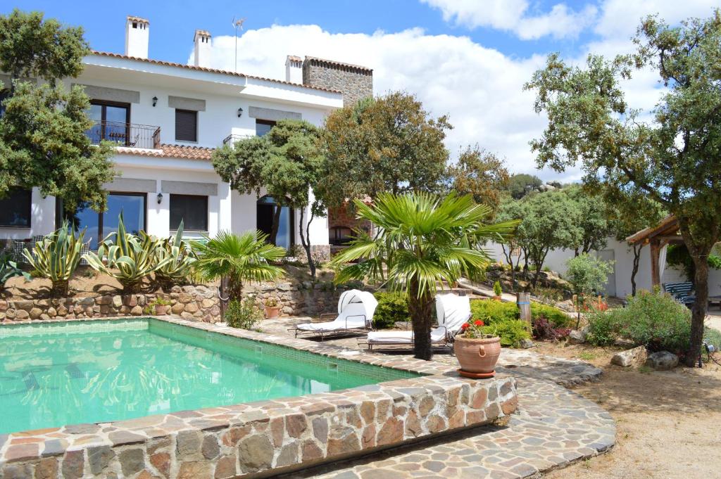 a swimming pool in front of a house at La Casona del Torcon in Navahermosa
