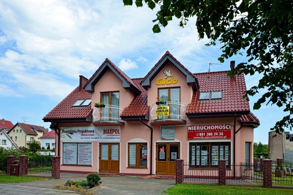 um edifício cor-de-rosa com um telhado vermelho em Gucio Domek Gościnny em Rewal