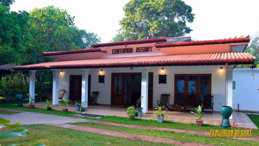 uma pequena casa branca com um telhado vermelho em Centurion Resort em Habarana