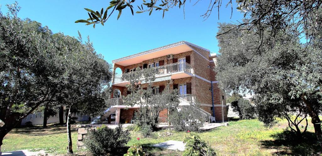 un edificio in mattoni con alberi di fronte di Villa Giardino Sa Tiacca a SantʼAndrea