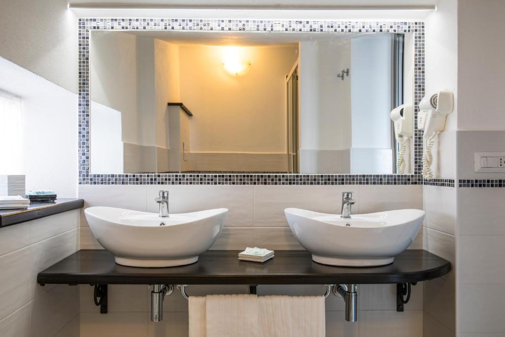 a bathroom with two sinks and a large mirror at Hotel La Playa in Cala Gonone