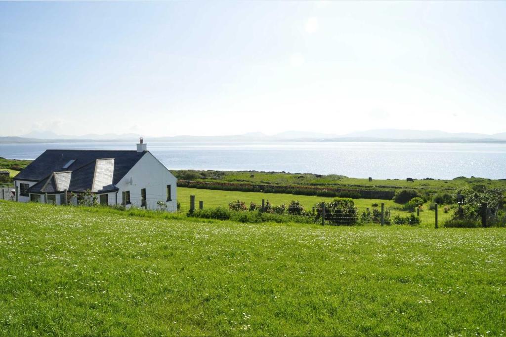 a white church on a hill with a green field at Portbahn, Bruichladdich in Bruichladdich