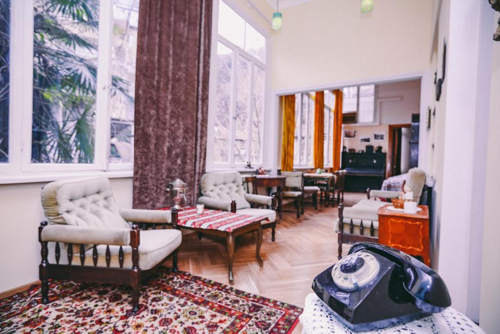 a waiting room with chairs and a table and windows at At Funicular Hostel in Tbilisi City