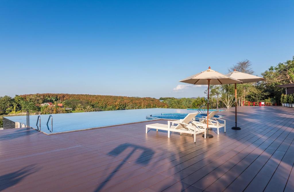 eine Terrasse mit 2 Stühlen, einem Sonnenschirm und einem Pool in der Unterkunft ChiangRai Lake Hill in Chiang Rai