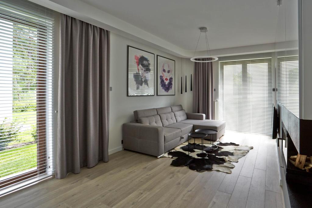 un salon avec un canapé et quelques fenêtres dans l'établissement Apartament Baltica z ogródkiem - w ustronnym miejscu tuż przy plaży, à Rogowo