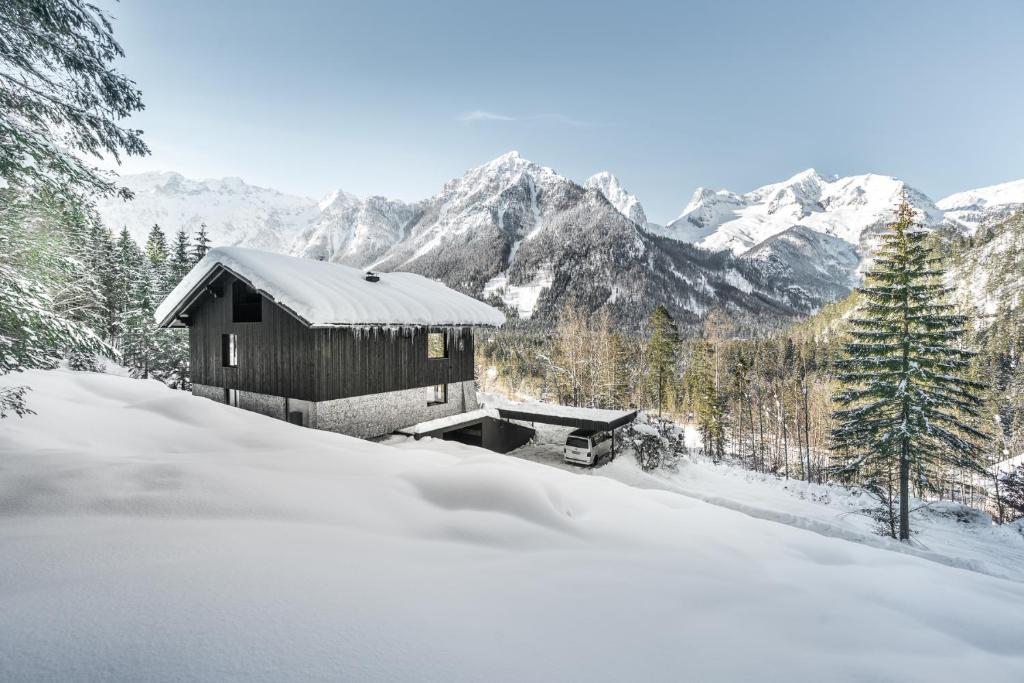 a cabin in the snow with mountains in the background at Luxus Chalet Quellhaus in Hinterstoder