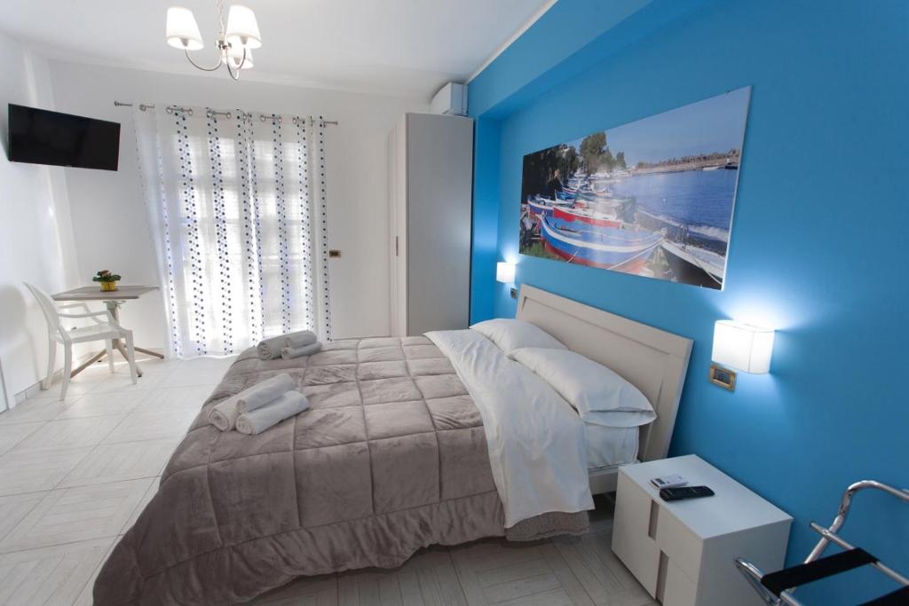 een slaapkamer met een blauwe muur met een bed en een tafel bij B&B Al Duomo Milazzo in Milazzo