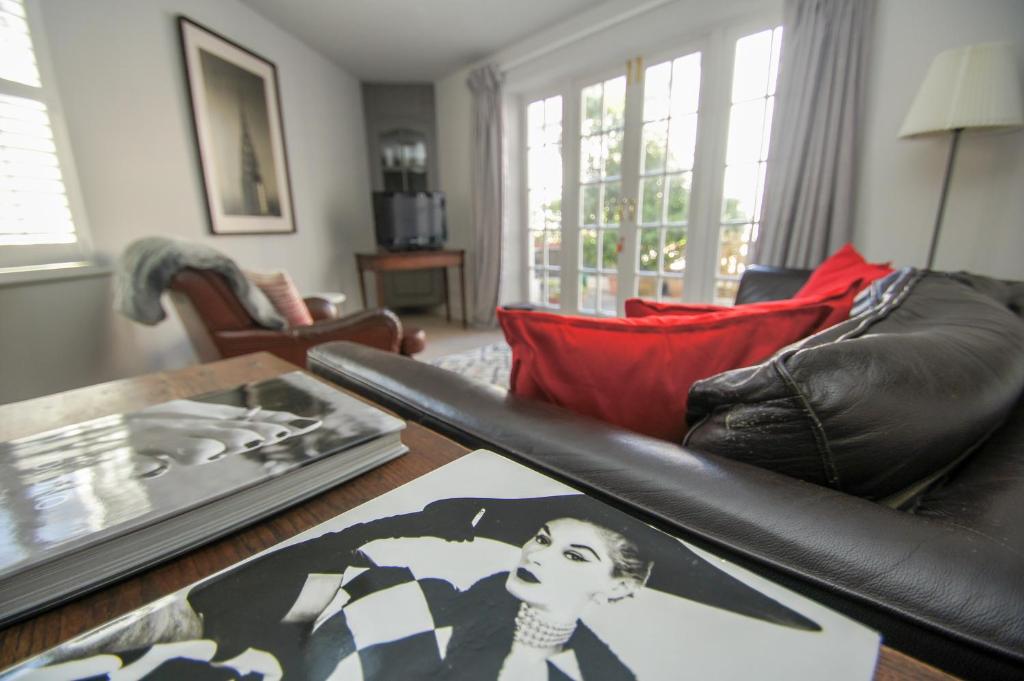 a living room with a black leather couch and a table at Arundel Mews - Parking - by Brighton Holiday Lets in Brighton & Hove