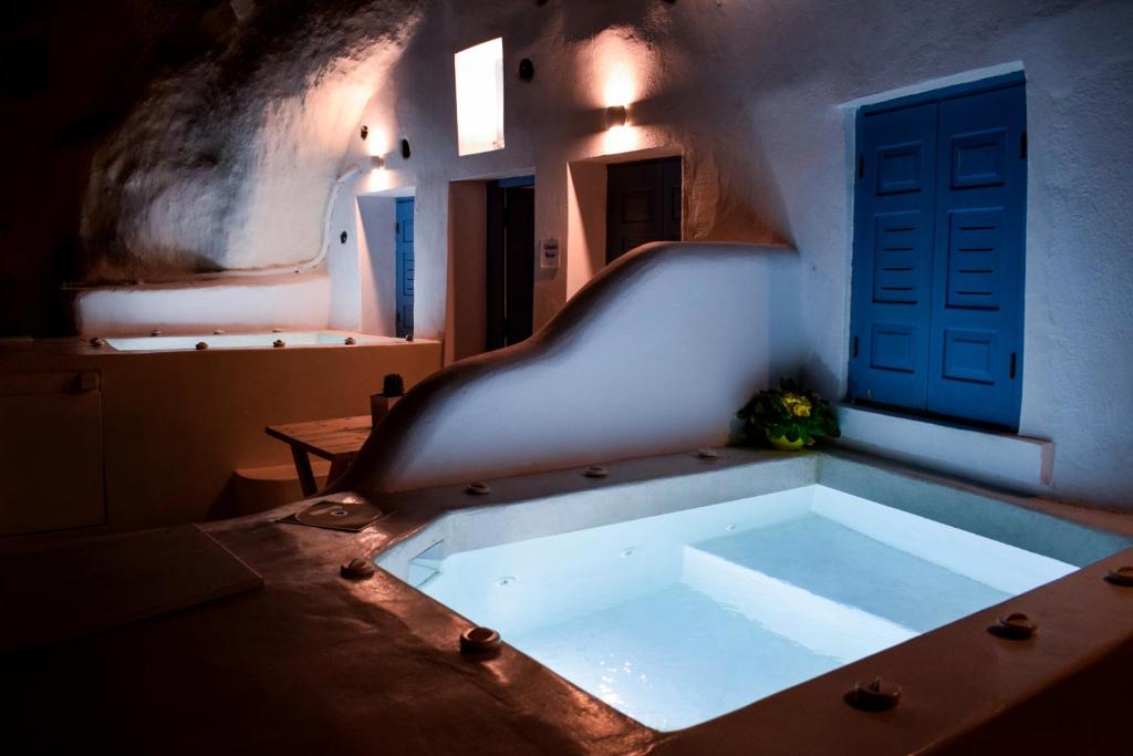 una vasca da bagno in una stanza con porta blu di Stoa Cave Villas a Mesariá