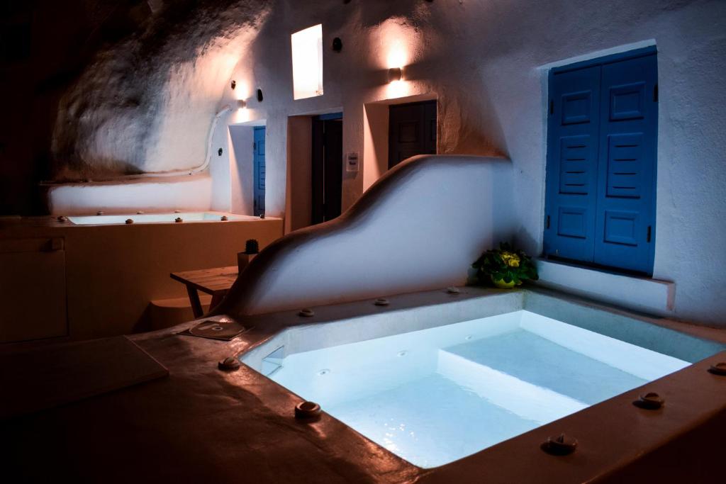 a bath tub in a room with a blue door at Stoa Cave Villas in Mesaria
