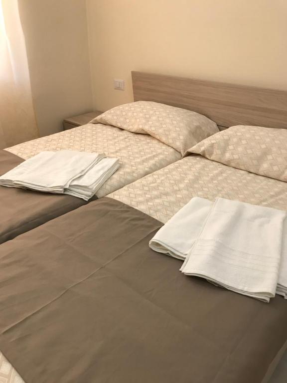 un letto con lenzuola e cuscini bianchi di B&B Trieste Caltanissetta a Caltanissetta