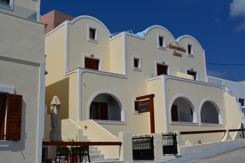 a large white building with a table in front of it at Anemomilos Suites in Fira