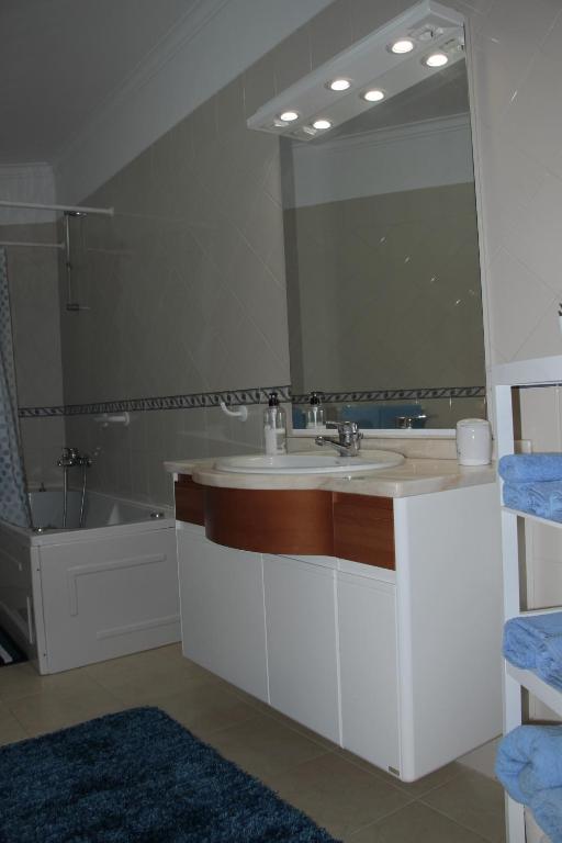 a bathroom with a sink and a large mirror at Ericeira Sunset Apartment in Ericeira
