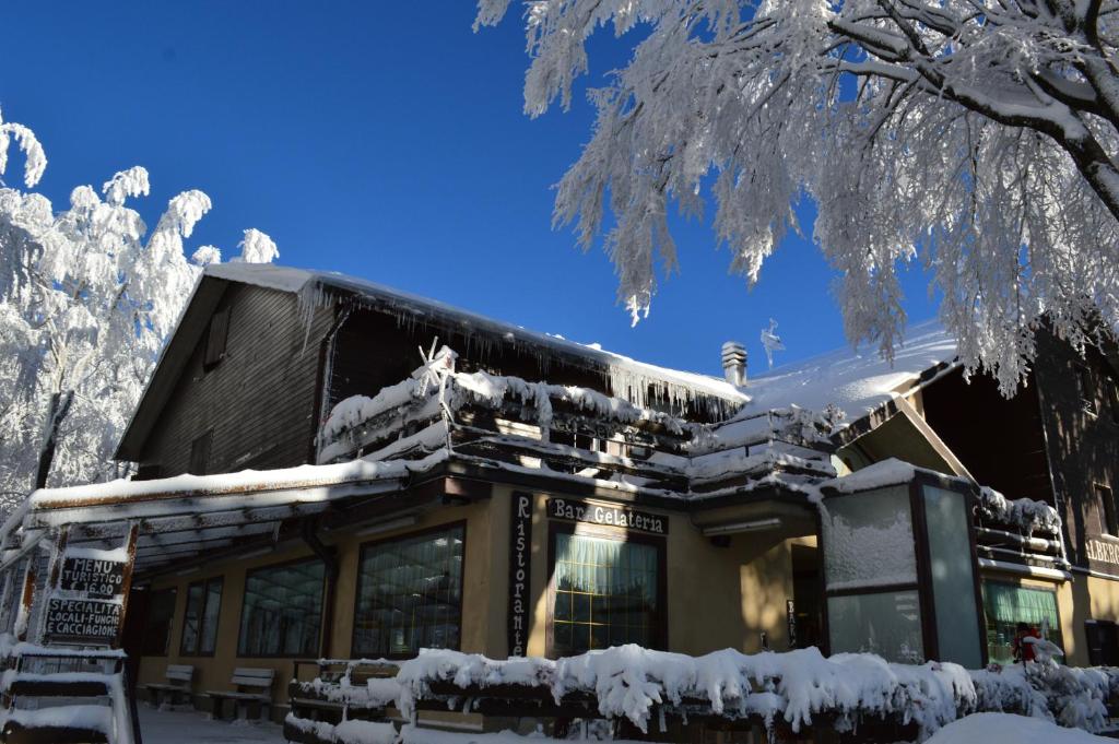 un edificio cubierto de nieve junto a un árbol en Albergo Sella - Monte Amiata, en Abbadia San Salvatore