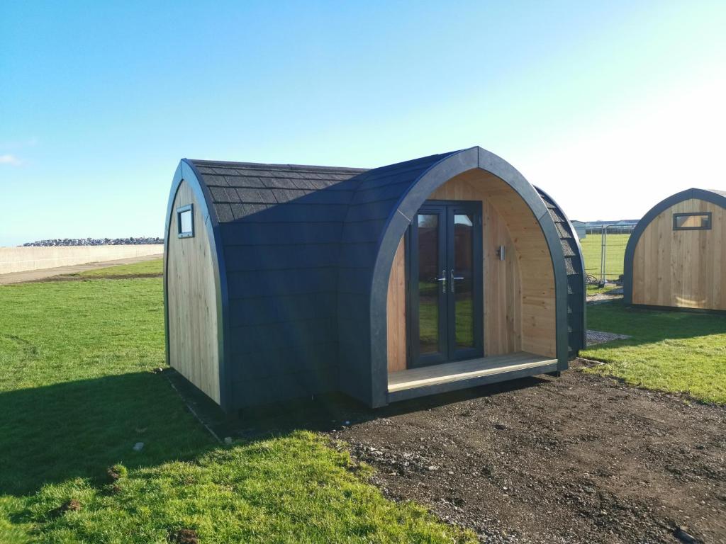 een klein houten gebouw midden in een veld bij Camping Pods, Seaview Holiday Park in Whitstable