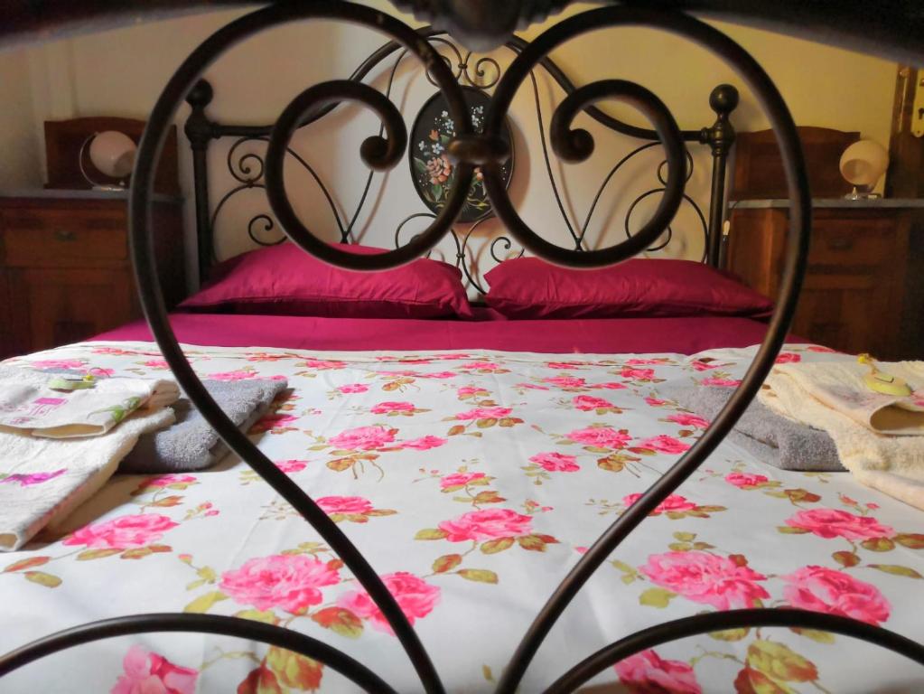 Cama negra con colcha floral y almohadas rojas en Camere Mazzini 49 en Sansepolcro