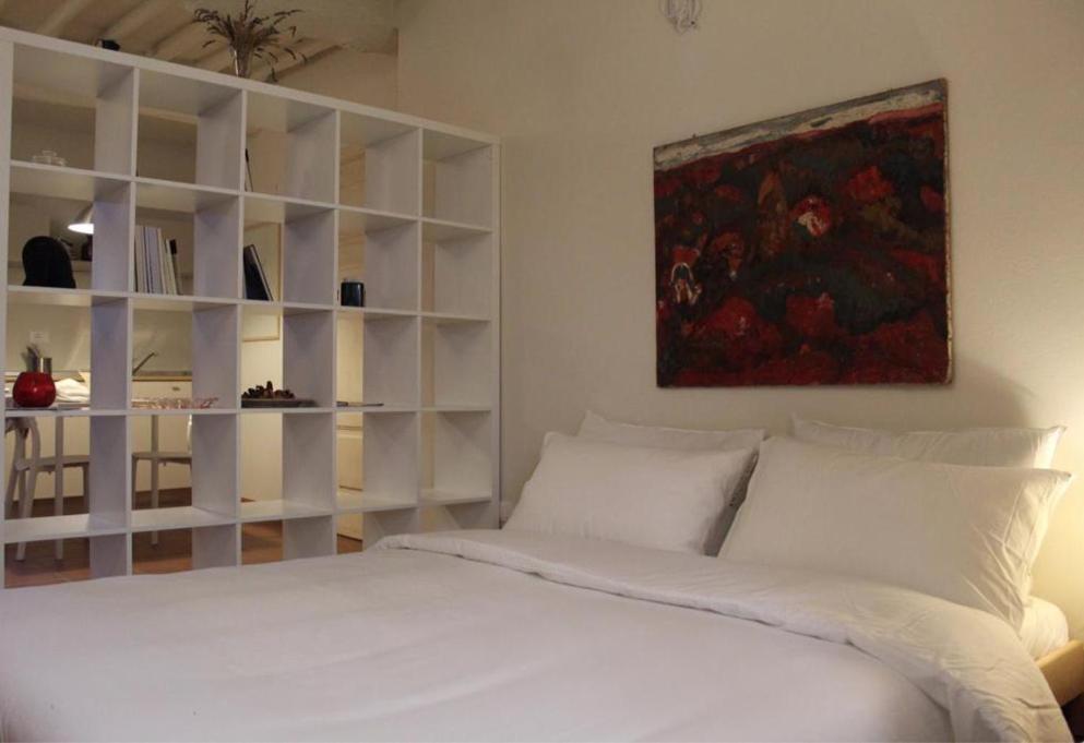 een slaapkamer met een wit bed en een schilderij aan de muur bij appartamento San Tommaso in Lucca
