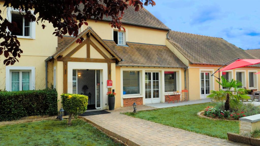 a house with a front yard with a driveway at Hôtel HAPY in Houdan