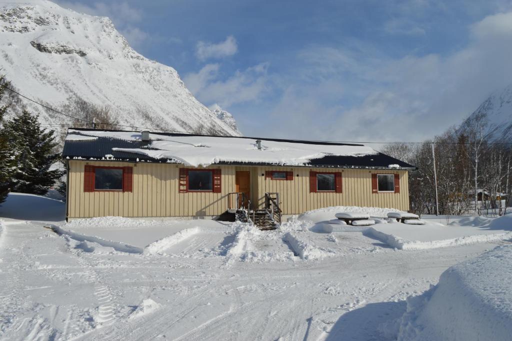 una cabaña en la nieve con una montaña cubierta de nieve en Lyngenfjord, Frøyas hus en Olderdalen