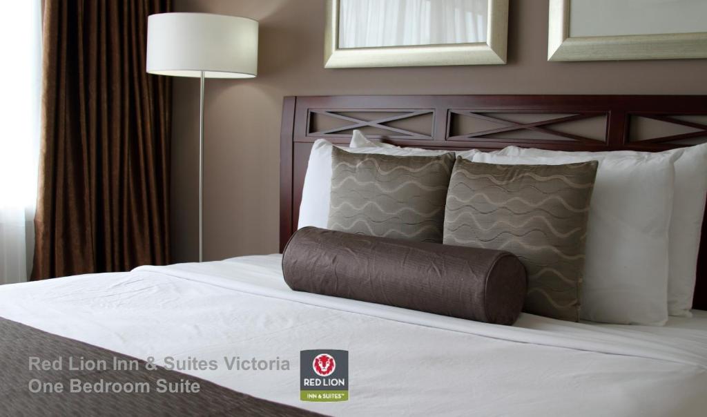 a bed in a hotel room with a brown pillow at Red Lion Inn and Suites Victoria in Victoria