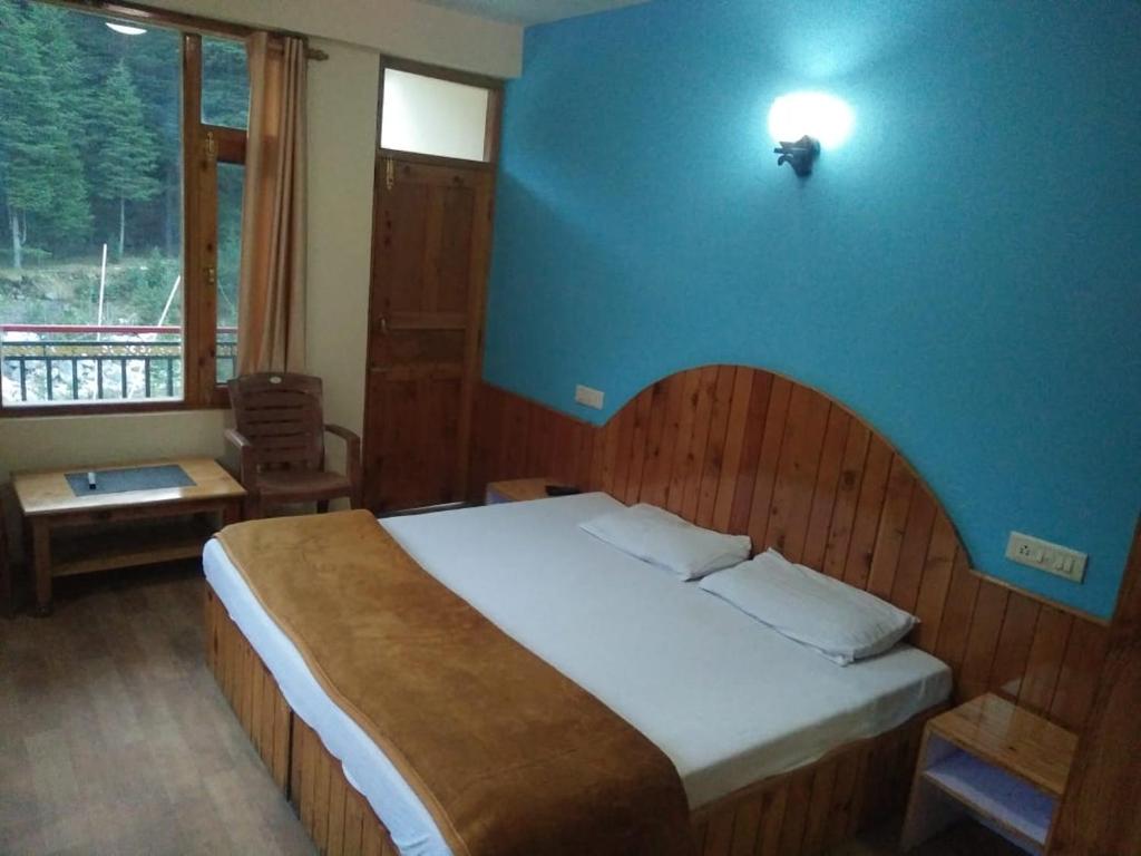 a bedroom with a large bed with a blue wall at Homestay Near Club House in Manāli