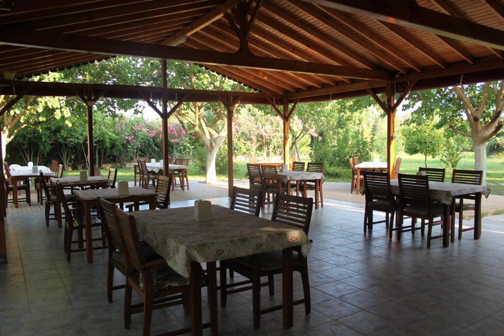 Un comedor al aire libre con mesas y sillas. en Ozge Bungalow Hotel, en Cıralı