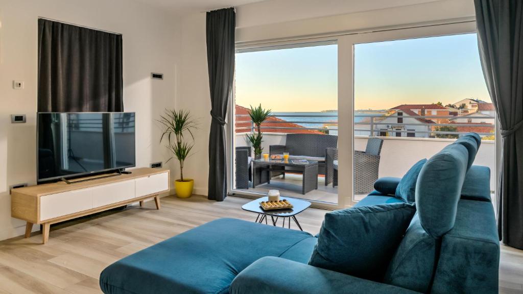 a living room with a blue couch and a television at Sun & Salt Apartments in Bibinje