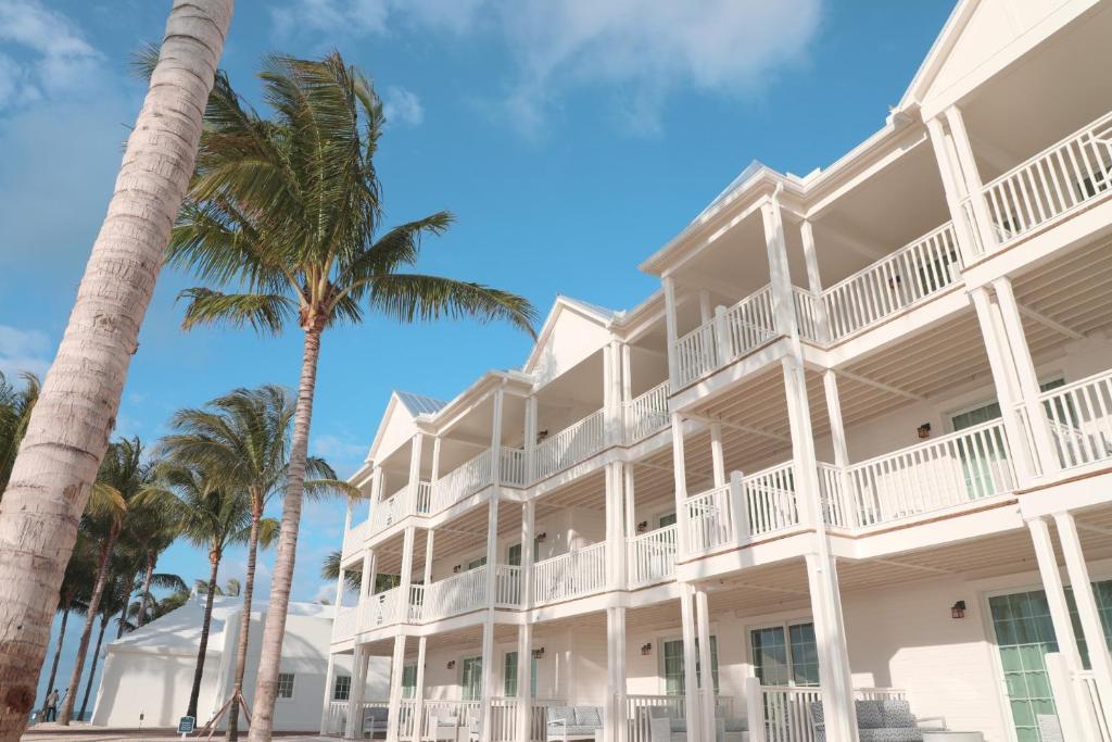 a white building with palm trees in front of it at Isla Bella Beach Resort & Spa - Florida Keys in Marathon