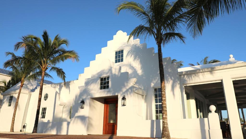 a white building with palm trees in front of it at Isla Bella Beach Resort & Spa - Florida Keys in Marathon