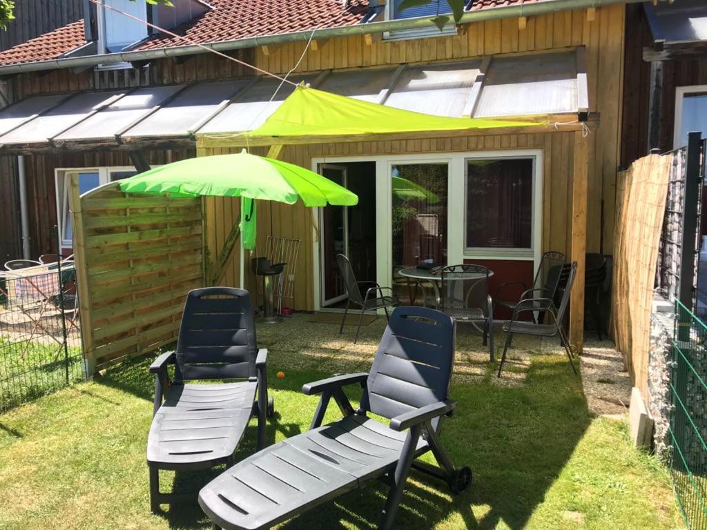 dos sillas y un paraguas verde en un patio en Ferienhäuser Schlossberg, en Zandt