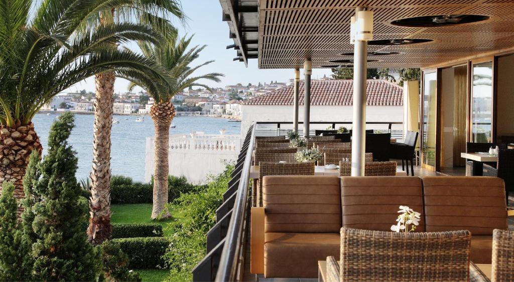 a restaurant with palm trees and a view of the water at Spetses Hotel in Spetses
