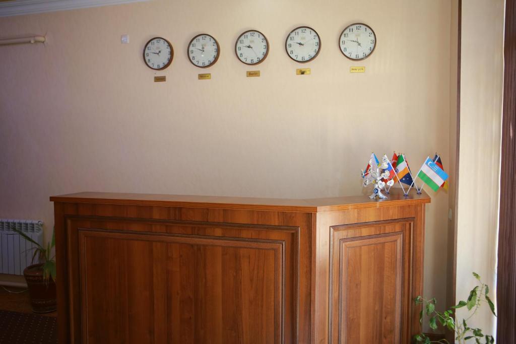 cztery zegary na ścianie nad drewnianą szafką w obiekcie Xum Don w Samarkandzie