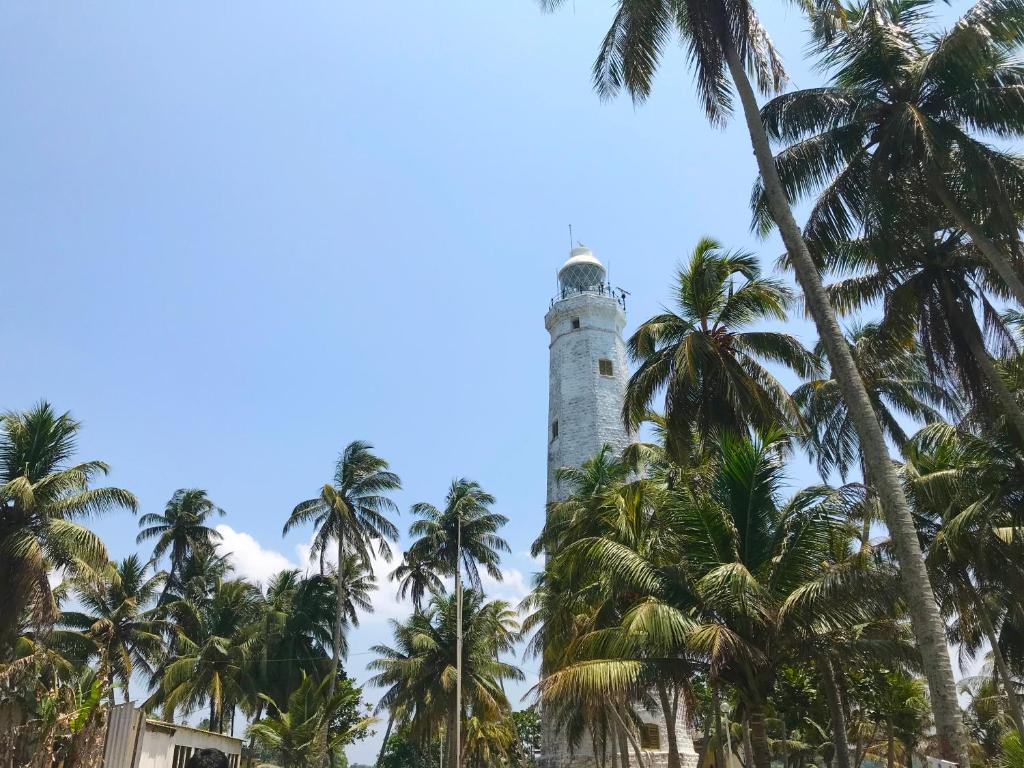 a lighthouse with palm trees in front of it at Light House Beach Resort in Matara