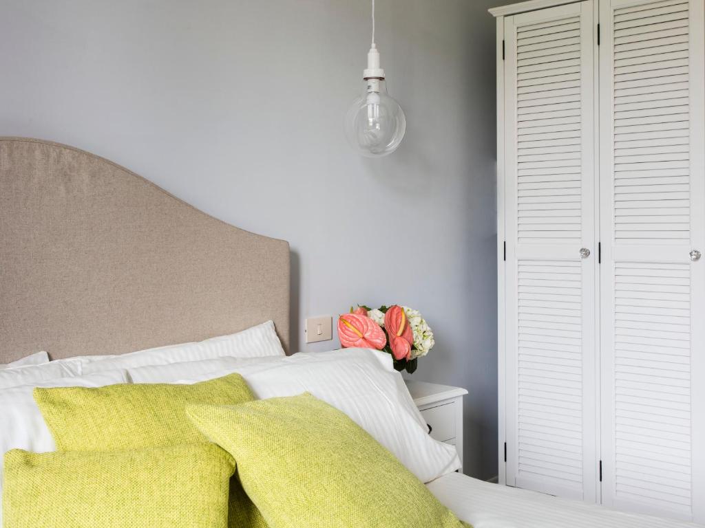 a bedroom with a bed with white sheets and yellow pillows at Punta Ala Sea View Apartments in Punta Ala