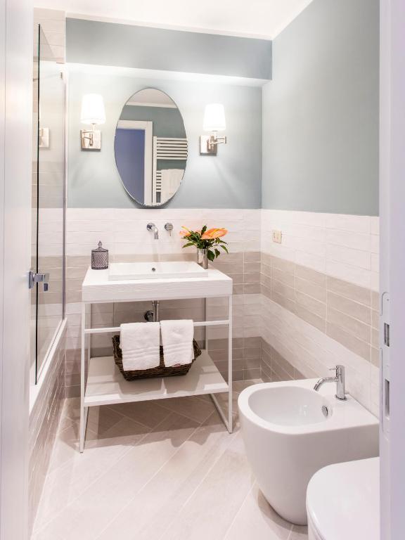 a white bathroom with a sink and a mirror at Punta Ala Sea View Apartments in Punta Ala