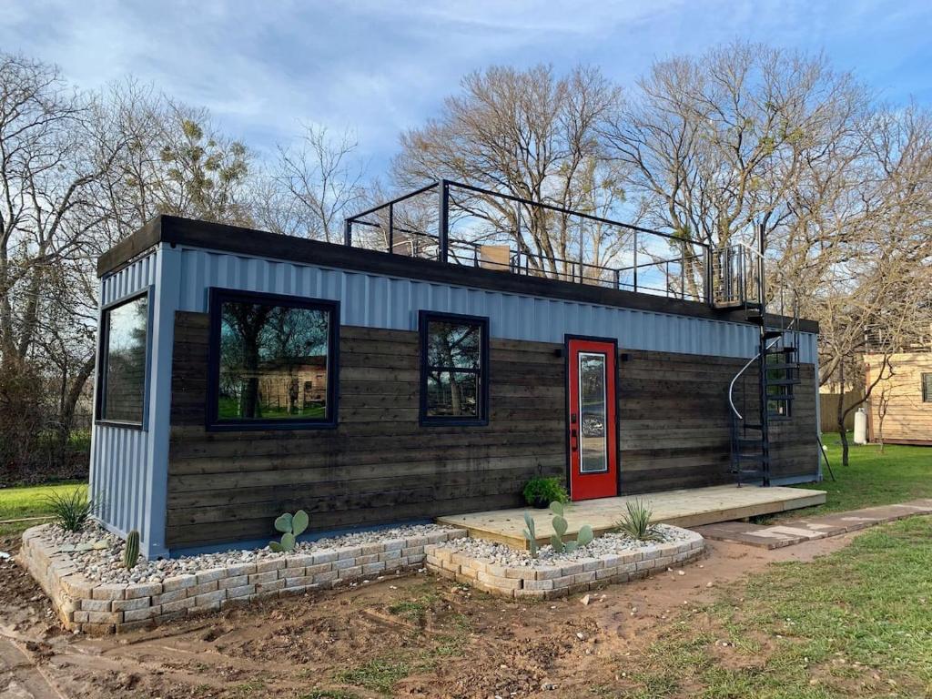a tiny house with a red door in a yard at The Hacienda Beautiful New Container Home 12 min to Magnolia in Waco