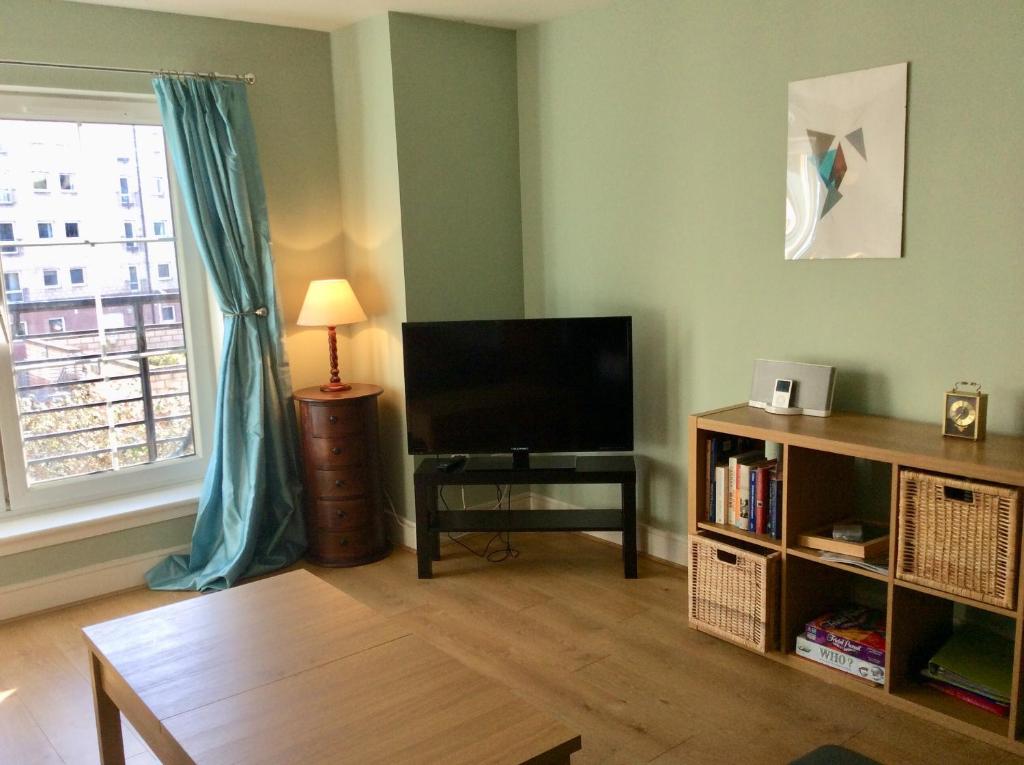 a living room with a flat screen tv and a window at 20/5 Timber Bush in Edinburgh