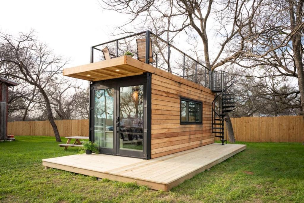 a tiny house on a deck in a yard at Tiny CargoHome near Magnolia Silos Baylor in Waco